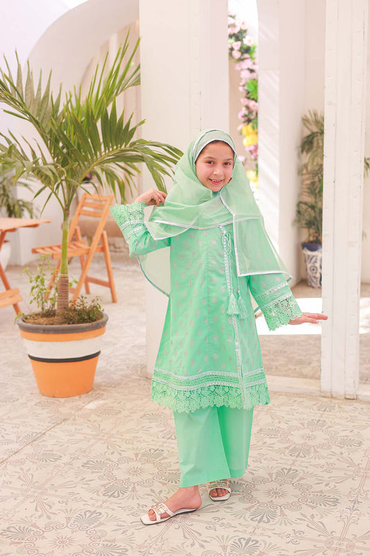 A girl wearing a green Angrakha frock with embroidery and lace details, paired with matching trousers, posing outdoors.