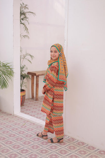 Woman in a colorful traditional outfit standing in a room with plants and a mirror.