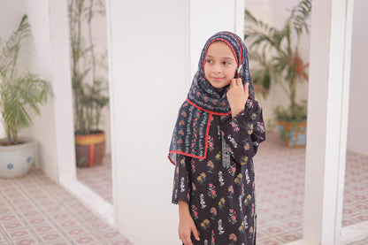 Young girl wearing a floral dress and headscarf in a room with plants.