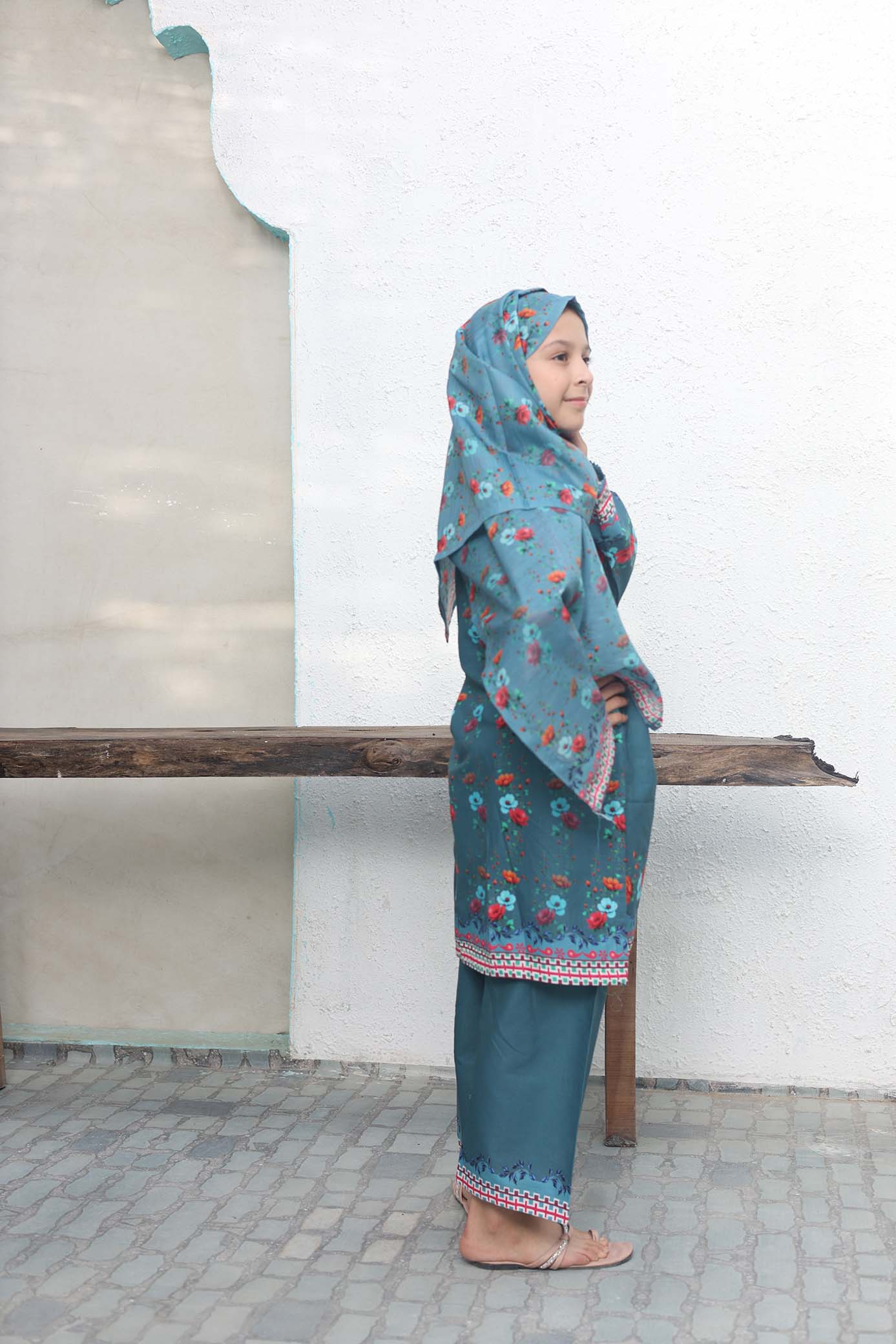 Person wearing a blue floral outfit standing against a white wall.