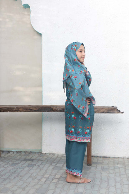Person wearing a blue floral outfit standing against a white wall.