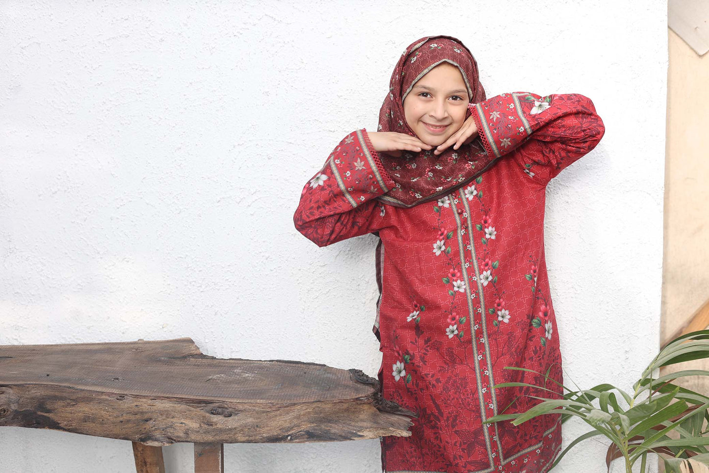 Woman in a red traditional outfit with floral patterns standing indoors.