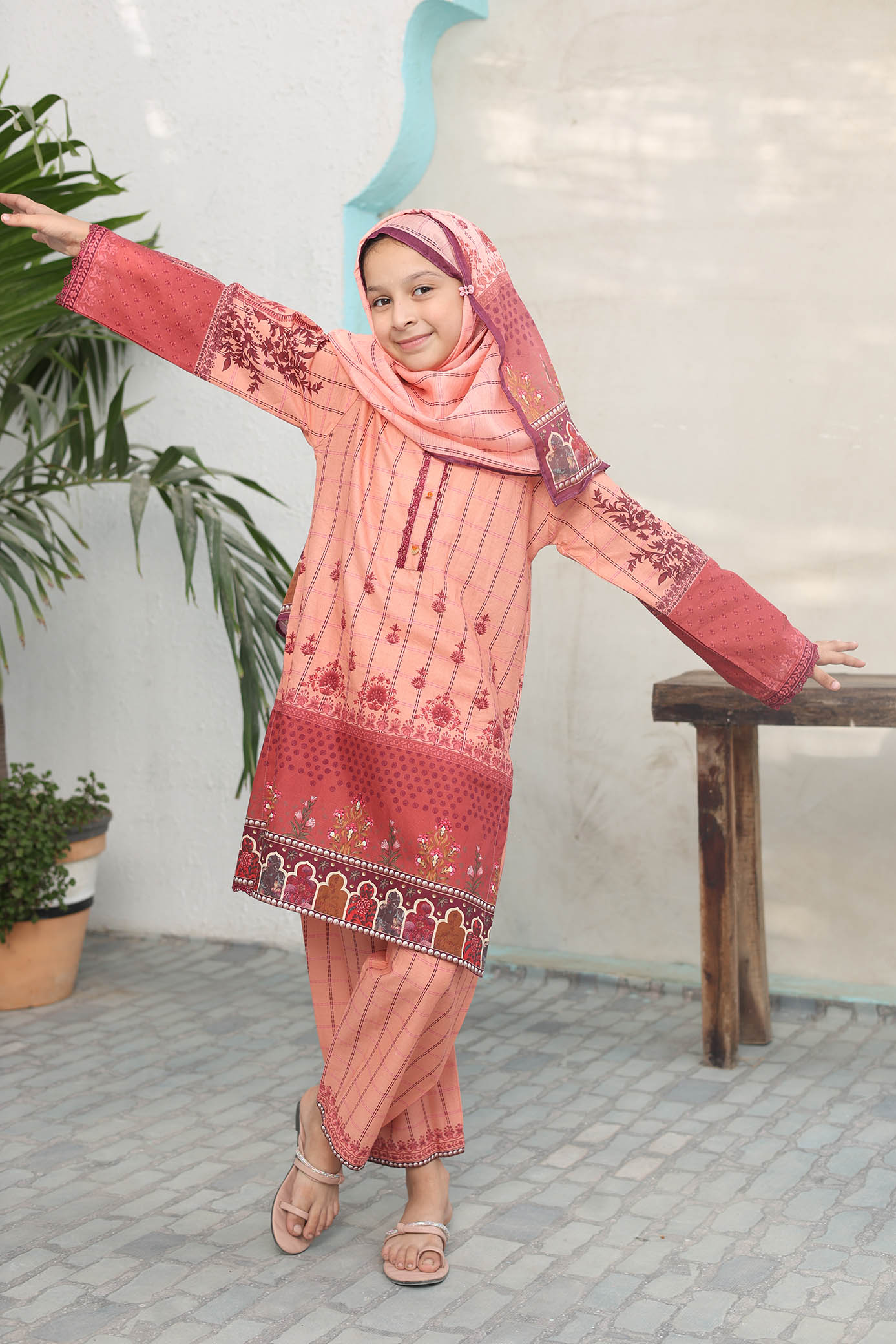 Child wearing a pink traditional outfit with floral patterns indoors.