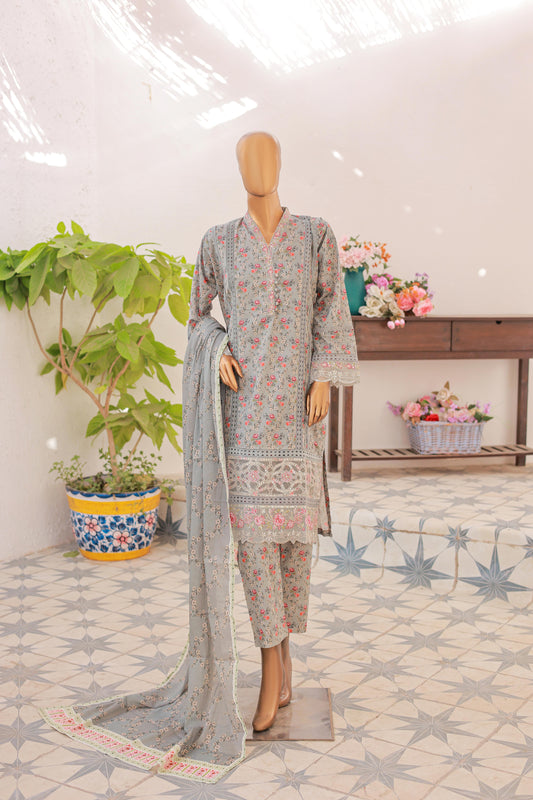 A mannequin displaying a three-piece silver festive embroidered outfit, consisting of a shirt, trousers, and a dupatta, set against a backdrop with floral elements and a wooden structure.