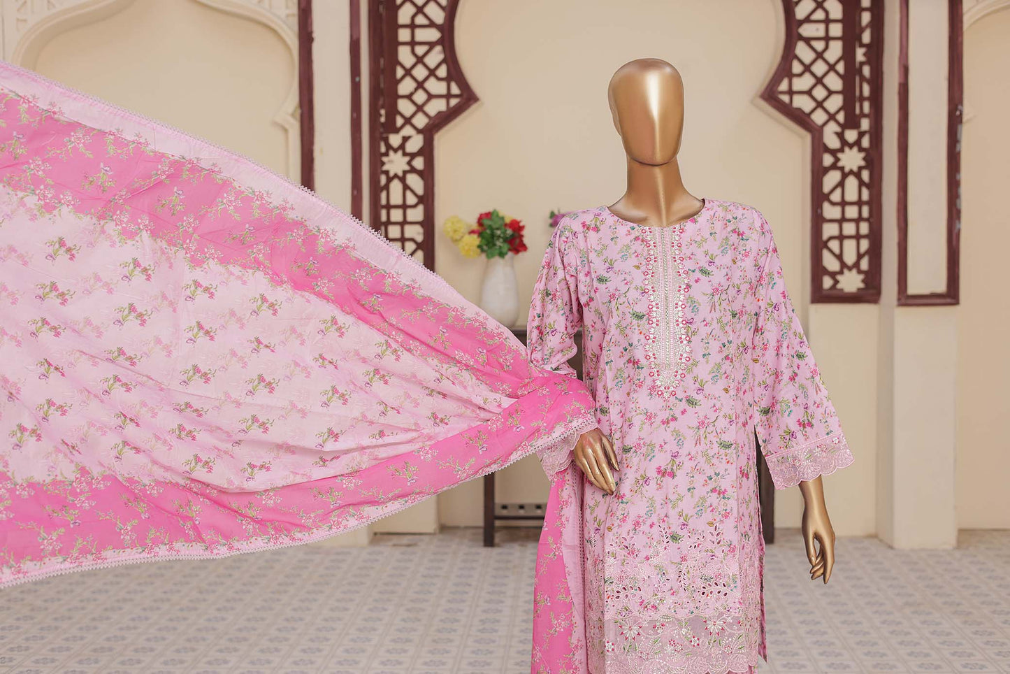 Mannequin wearing a pink floral dress with a matching pink dupatta in a room with decorative elements.