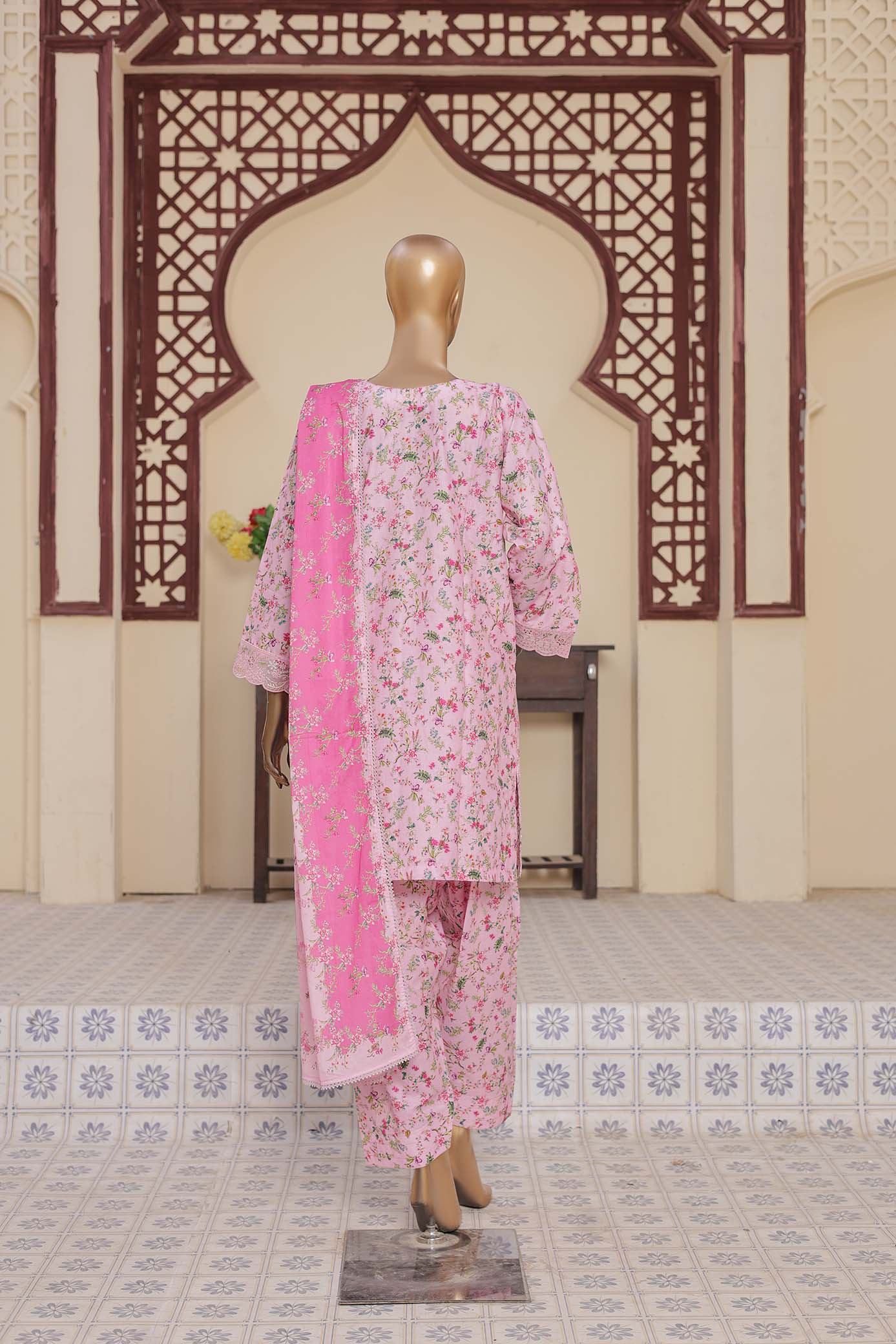 Mannequin wearing a pink floral outfit with a matching dupatta against a decorative wall.