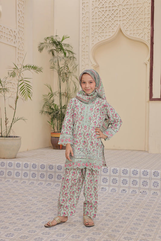 Young girl in a floral outfit standing in a decorated indoor setting with plants and an archway.