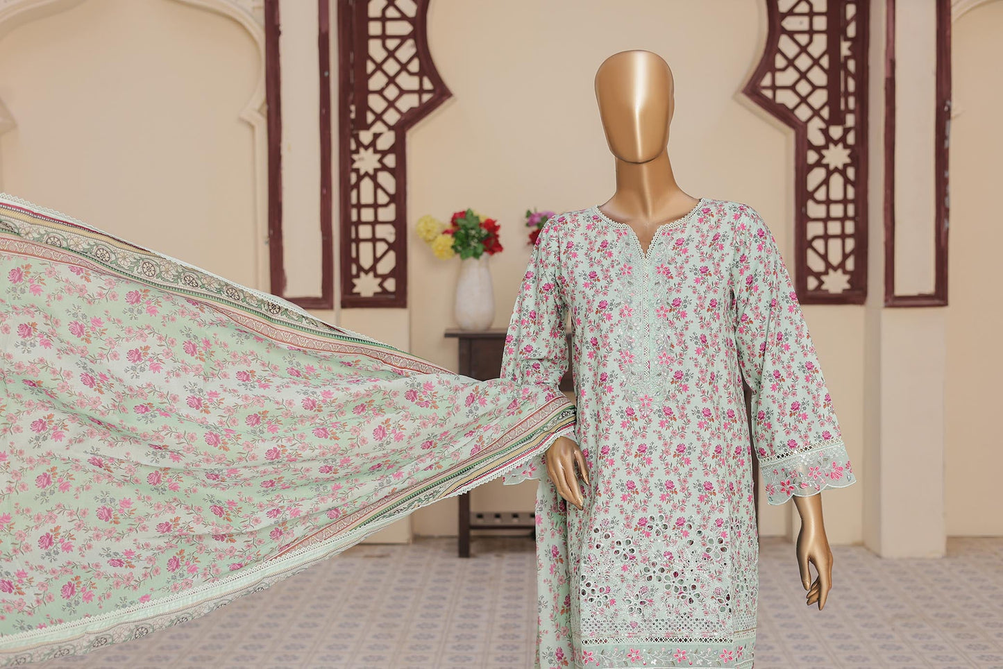 Mannequin wearing a floral dress with a matching dupatta in a room setting.