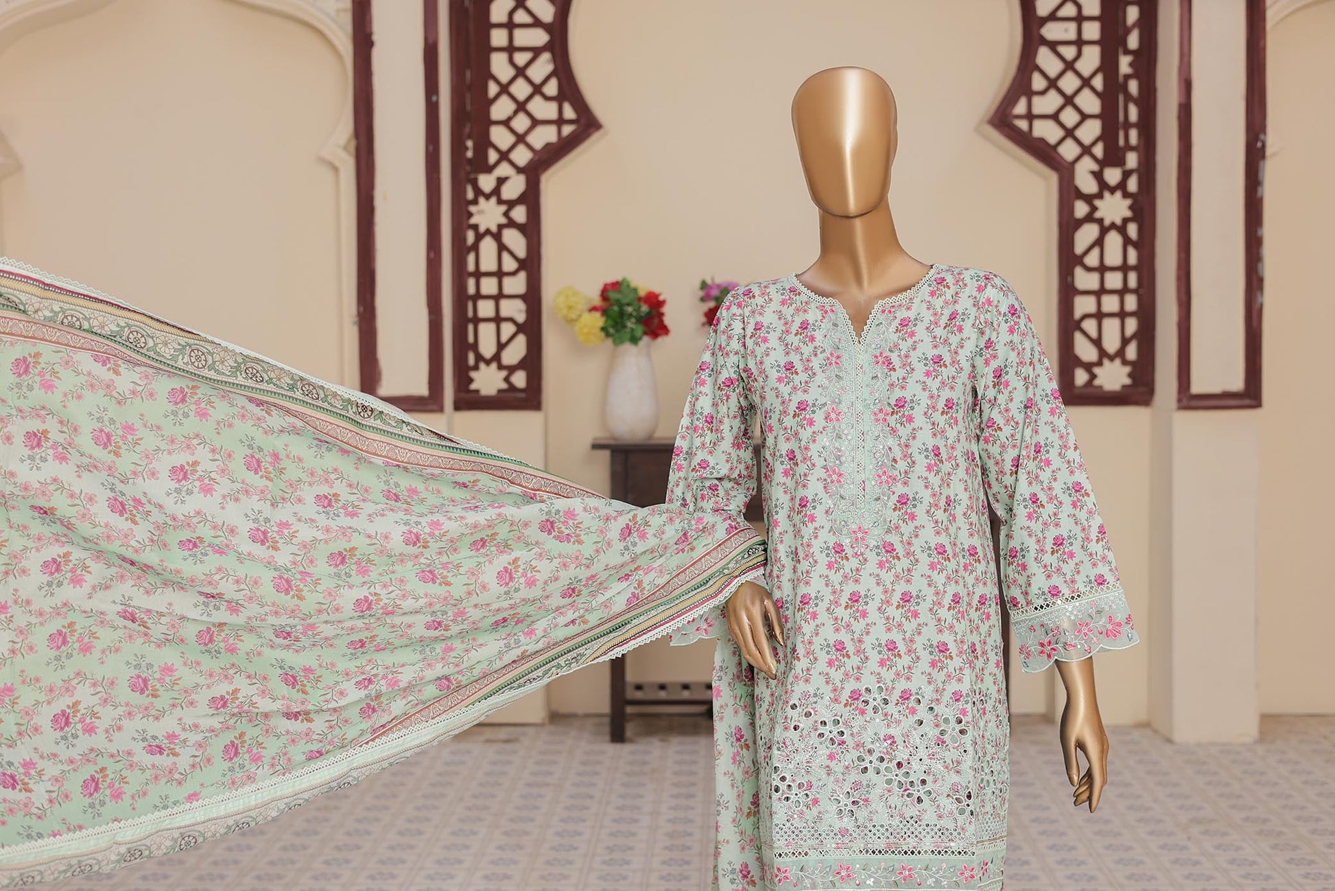 Mannequin wearing a floral dress with a matching dupatta in a room setting.