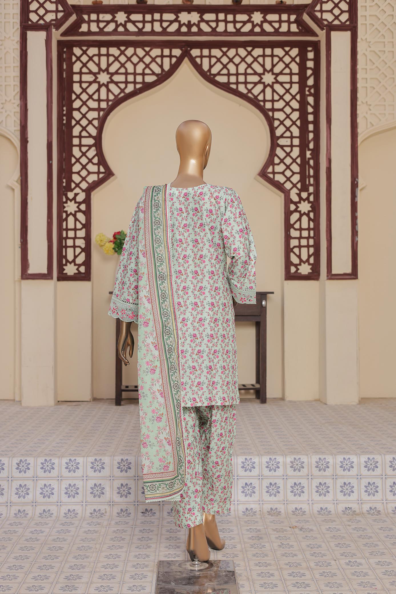 Mannequin wearing a floral outfit in a decorated room with intricate wall patterns.