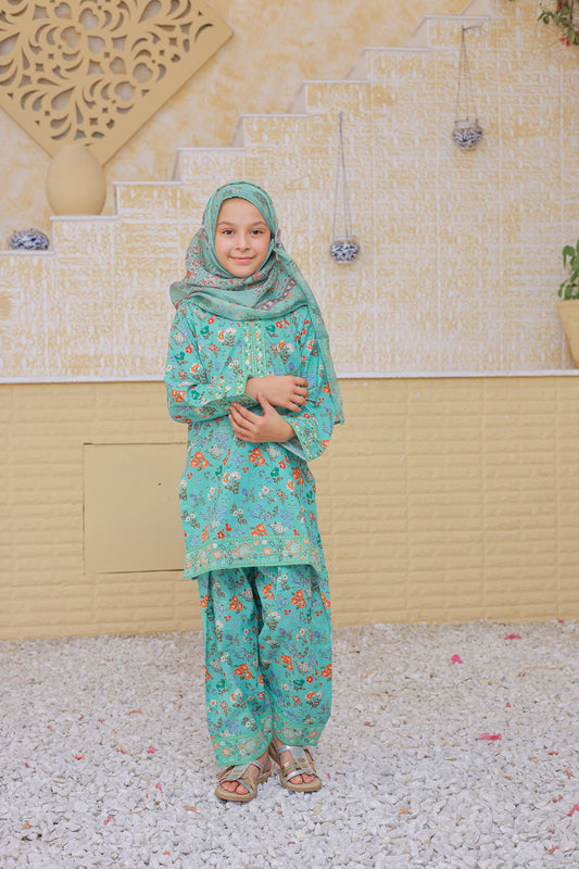 Child wearing a green floral outfit standing in front of a decorative wall.