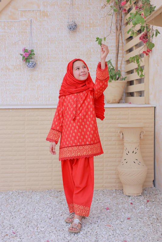Person wearing a red traditional outfit with a matching headscarf, standing outdoors.