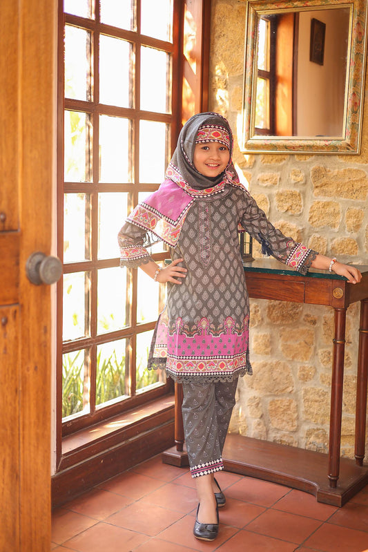 Woman in traditional attire standing in a room with stone walls and wooden furniture.