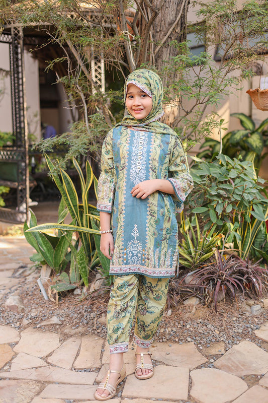 Child wearing a blue and green traditional outfit with a headscarf, standing outdoors among plants.