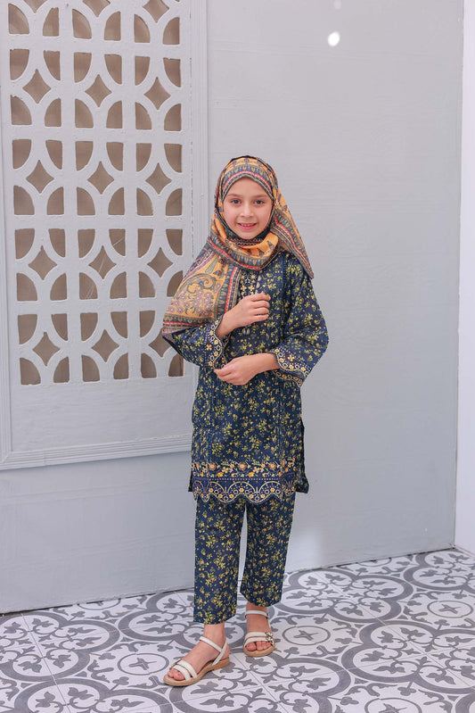A girl wearing a three-piece outfit with embroidered details, consisting of a shirt, trousers, and a dupatta, standing against an indoor background.