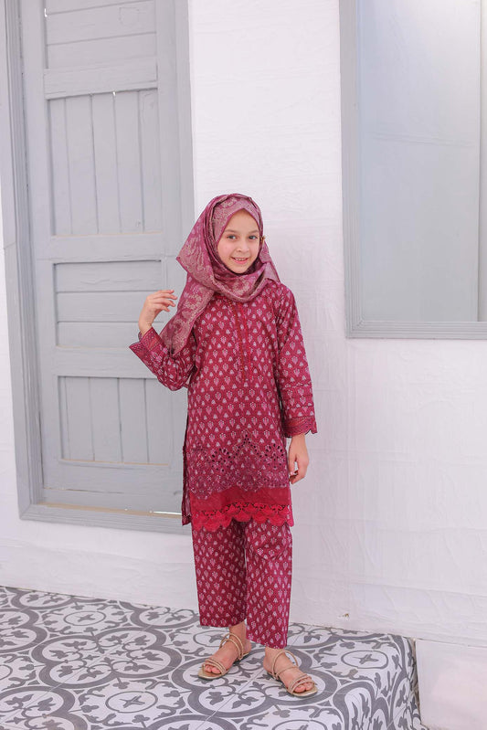 A young girl wearing a festive embroidered outfit in red and white, consisting of a shirt with sleeves, trousers, and a dupatta.