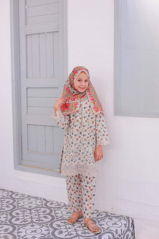 A young girl wearing a beige festive embroidered outfit with chikankari work on the front and sleeves, and a dupatta scarf.
