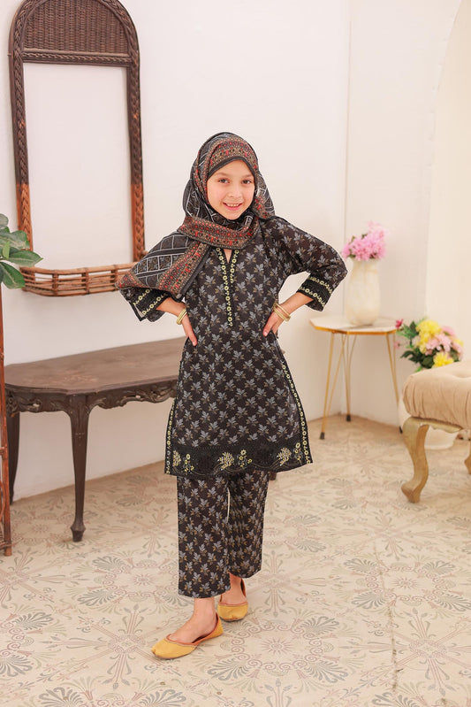 A girl wearing a black floral embroidered long-sleeved shirt, trousers, and a dupatta with a matching design, standing in a room with classic decor.